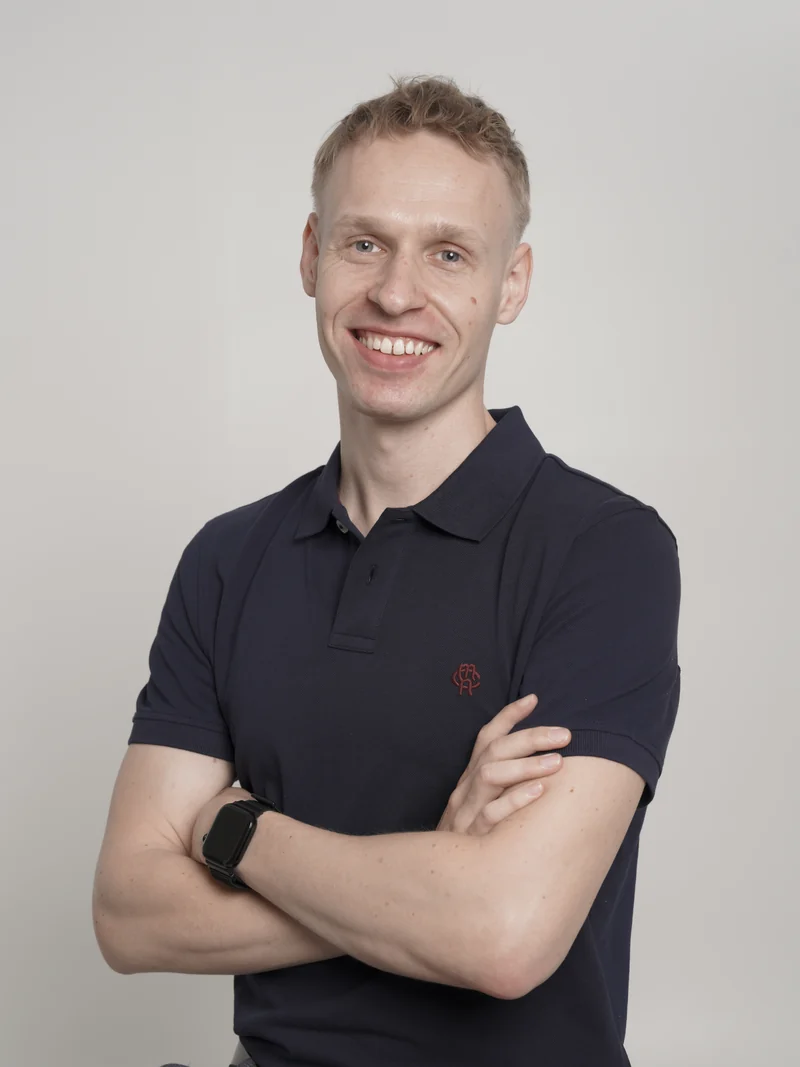 René Sass smiling with his arms folded, wearing a navy polo shirt